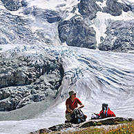 Walkers / Hikers resting with view over the Moiry Glacier in the Pennine Alps, Valais, Switzerland