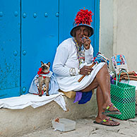 Licensed street model posing for tourists as colourful Cuban woman smoking huge Havana cigar with dressed cat in the streets of Old Havana / La Habana Vieja, Cuba