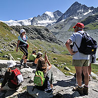 Tourists / Walkers walking along mountain path in the Pennine Alps, Valais, Switzerland